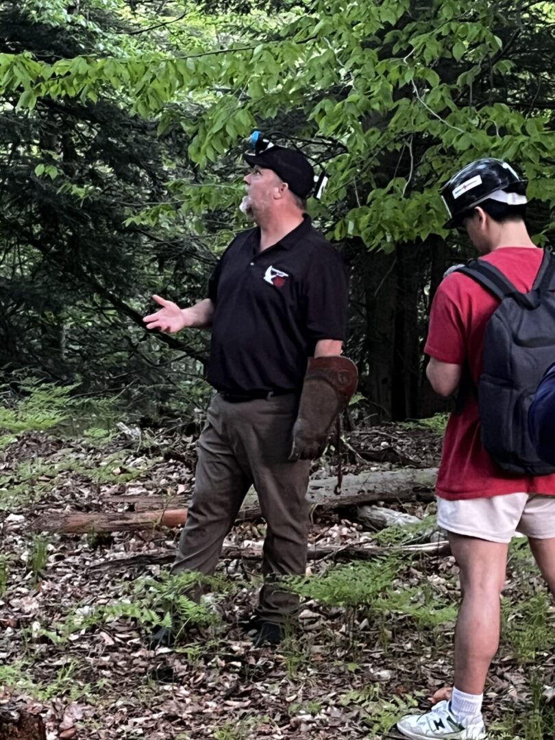 Two men walking in the woods with backpacks.